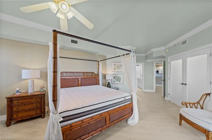 This bedroom features light-colored flooring and crown molding