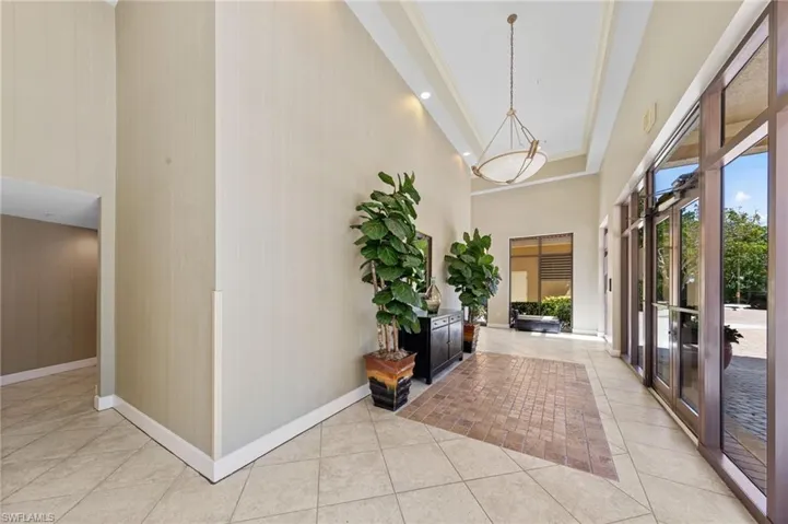 The entry features large format tile flooring, a tray ceiling with a hanging light fixture, and floor-to-ceiling windows