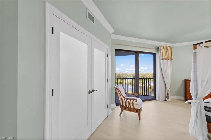 This room features light-colored flooring, direct access to a balcony with a water view, and crown molding