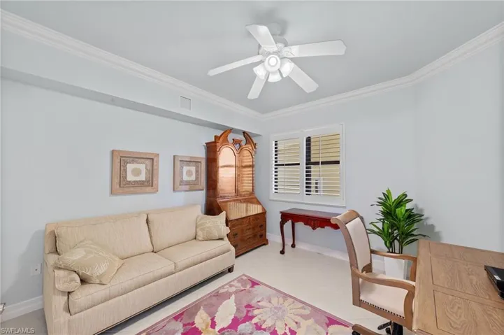 This room features white crown molding, a ceiling fan, and a window with white louvered shutters