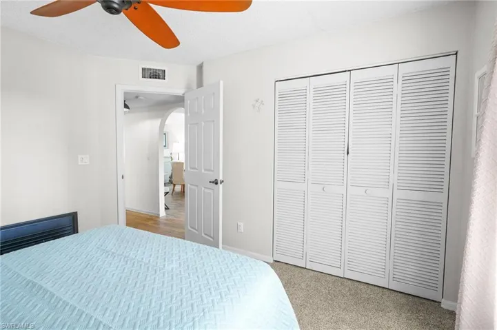 Bedroom featuring arched walkways, a ceiling fan, light carpet, a closet, and a textured ceiling