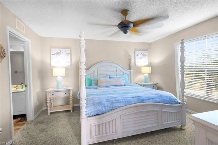 Bedroom featuring carpet flooring, a textured ceiling, a ceiling fan, and ensuite bathroom