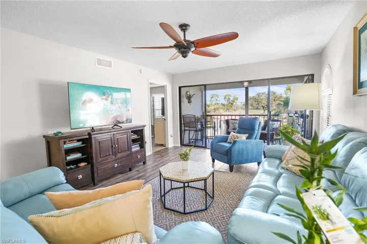 Living area featuring wood finished floors, a textured ceiling, and ceiling fan