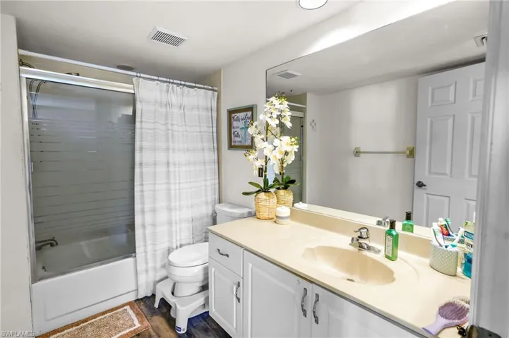 Bathroom featuring vanity, shower / tub combo, and dark wood-type flooring