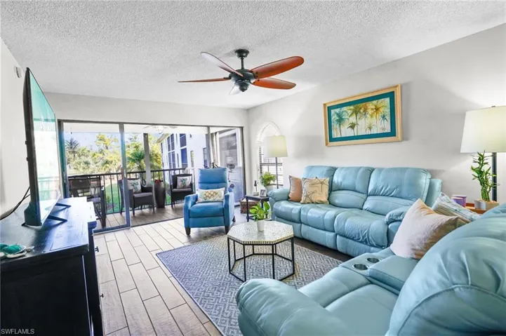 Living area featuring wood finished floors, a ceiling fan, and a textured ceiling
