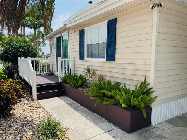 Exterior with horizontal siding, a private deck with white railings, a sliding glass entry door, and a landscaped planter box
