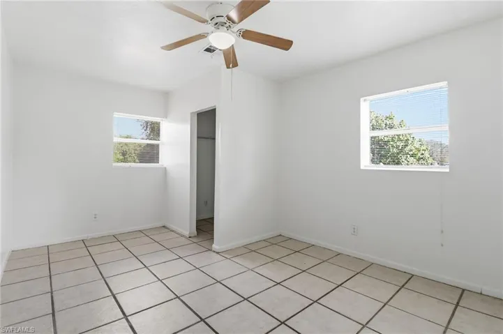Unfurnished bedroom with light tile patterned flooring, multiple windows, and a ceiling fan