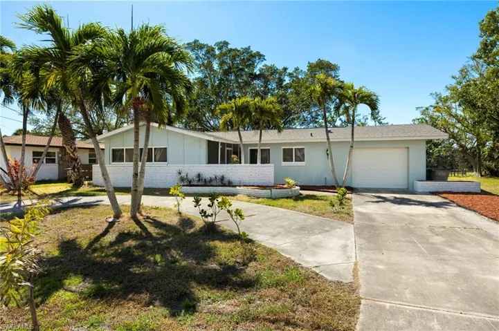 Single story home featuring a garage, concrete driveway, brick siding, a front yard, and roof with shingles