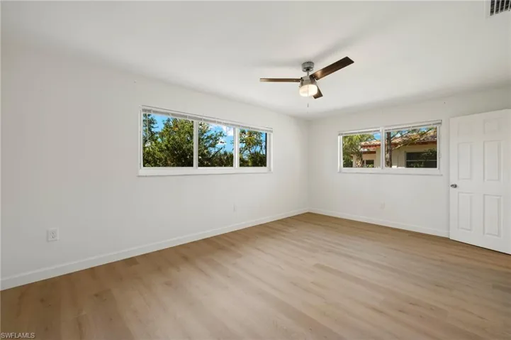 Empty room featuring healthy amount of natural light, light wood-style floors, and a ceiling fan