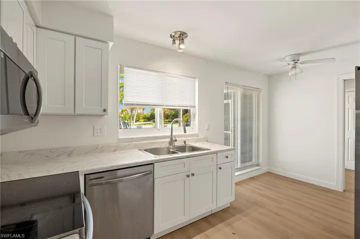Kitchen with stainless steel appliances, white cabinetry, and light countertops
