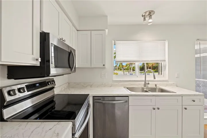 Kitchen featuring stainless steel appliances, light countertops, and white cabinetry
