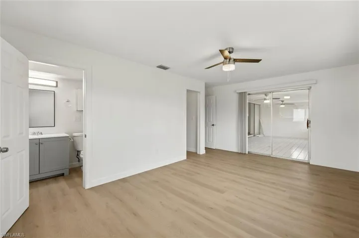 Unfurnished bedroom featuring ensuite bath, light wood-style floors, a ceiling fan, and a closet