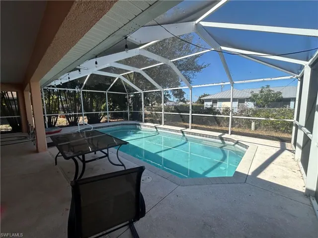 Swimming pool with a sunroom, a patio area, and glass enclosure
