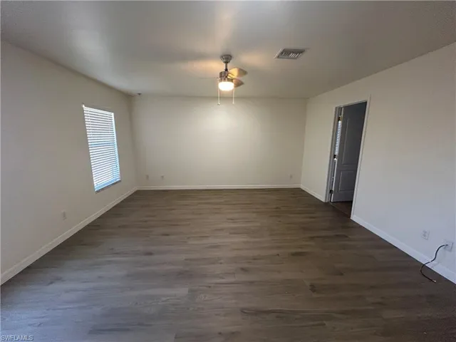 Spare room featuring dark wood-type flooring and ceiling fan