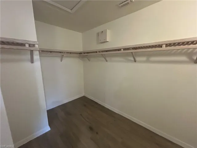 Walk in closet featuring dark wood-style floors and attic access