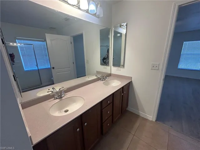Bathroom featuring double vanity and dark tile patterned floors