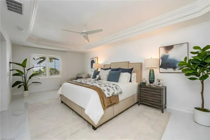 Bedroom with a ceiling fan, ornamental molding, and a tray ceiling