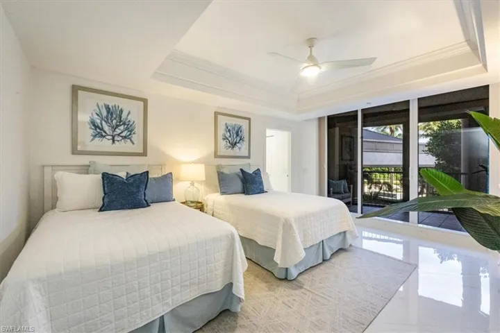 Bedroom with ornamental molding, access to exterior, a ceiling fan, and a raised ceiling
