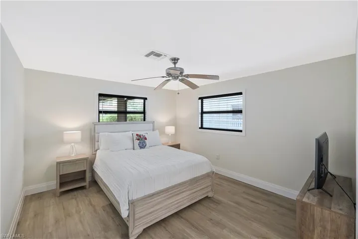 Bedroom featuring multiple windows, light wood-type flooring, and ceiling fan