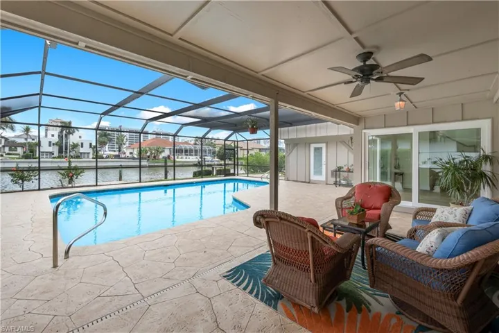 Swimming pool featuring a patio area, a sunroom, a lanai, a residential view, and a water view