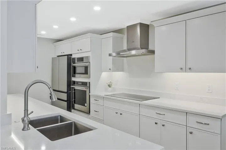 Kitchen featuring white cabinets, recessed lighting, light stone countertops, and stainless steel appliances