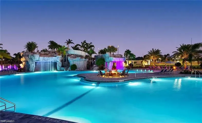 Pool at dusk featuring pool water feature
