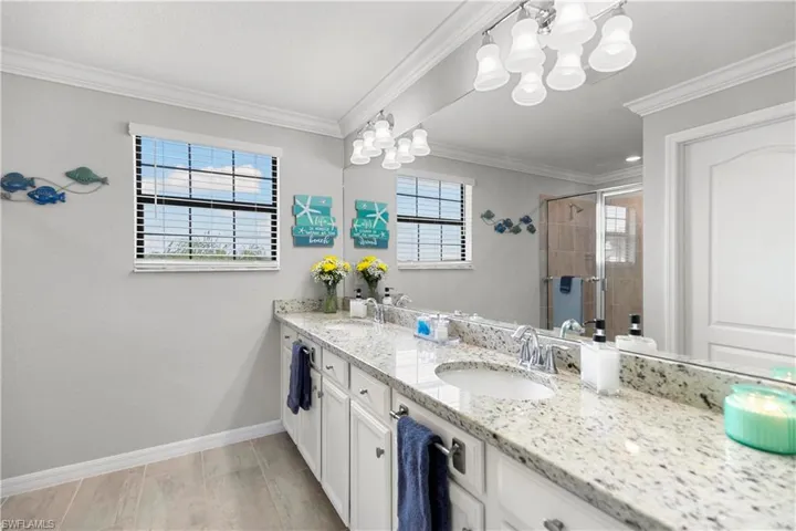 Bathroom with crown molding, walk in shower, and large double sink vanity.