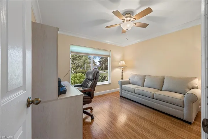 Office space featuring wood finished floors, a ceiling fan, crown molding, and baseboards