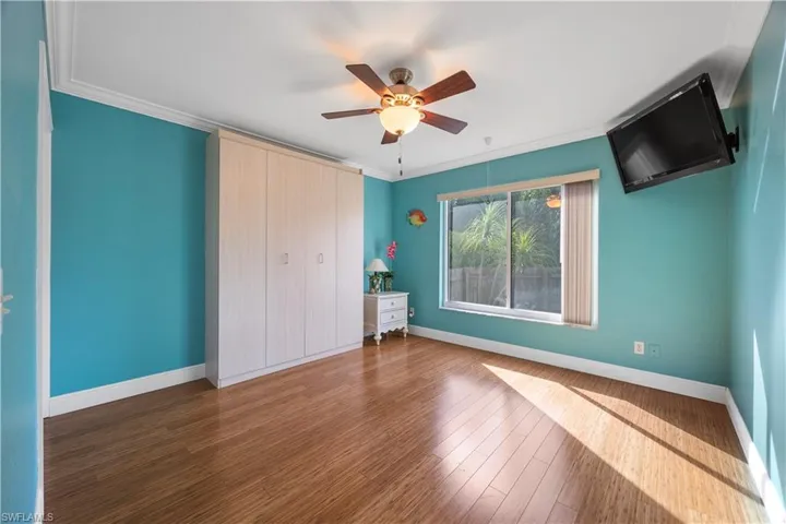 Unfurnished bedroom with ornamental molding, a ceiling fan, wood finished floors, and baseboards