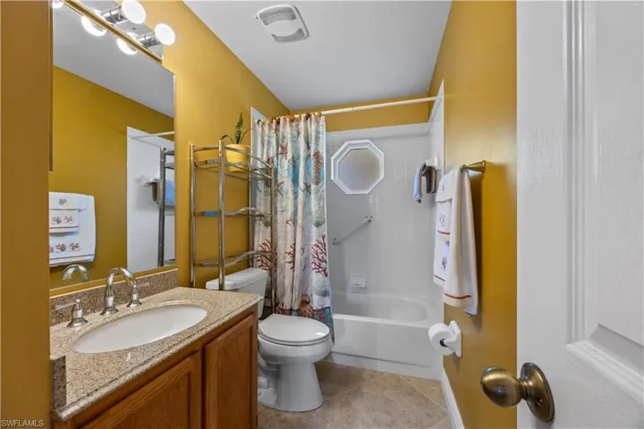 Full bathroom with shower / bath combo, toilet, tile patterned flooring, and vanity