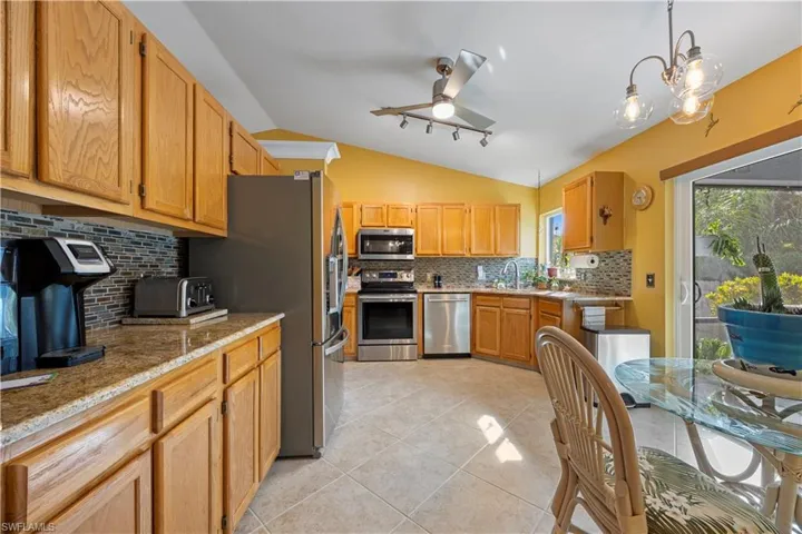 Kitchen featuring tasteful backsplash, stainless steel appliances, a sink, a ceiling fan, and lofted ceiling