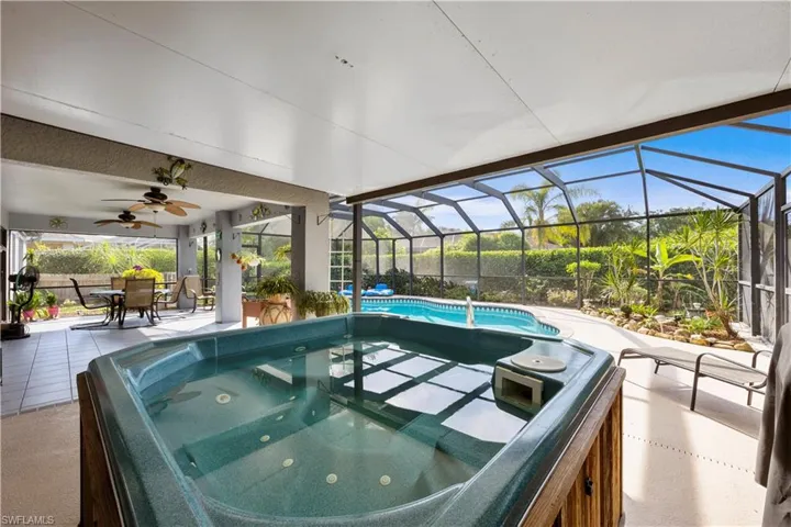 Outdoor pool featuring a patio area, a ceiling fan, outdoor dining space, a hot tub, and glass enclosure