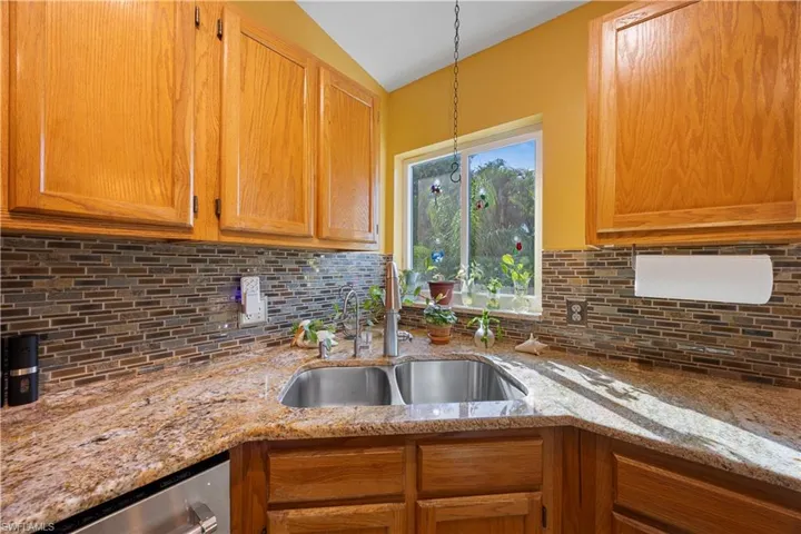 Kitchen with stainless steel dishwasher, backsplash, lofted ceiling, and a sink