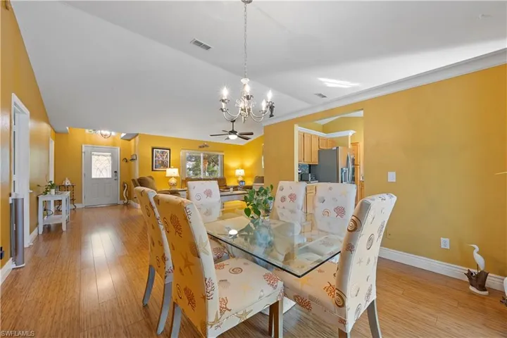 Dining space with ceiling fan with notable chandelier, visible vents, baseboards, and light wood-type flooring