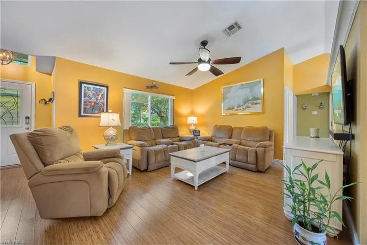 Living area featuring visible vents, ceiling fan, light wood finished floors, and vaulted ceiling