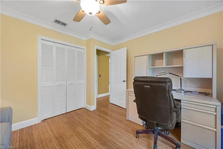Office area with light wood finished floors, crown molding, a ceiling fan, visible vents, and baseboards