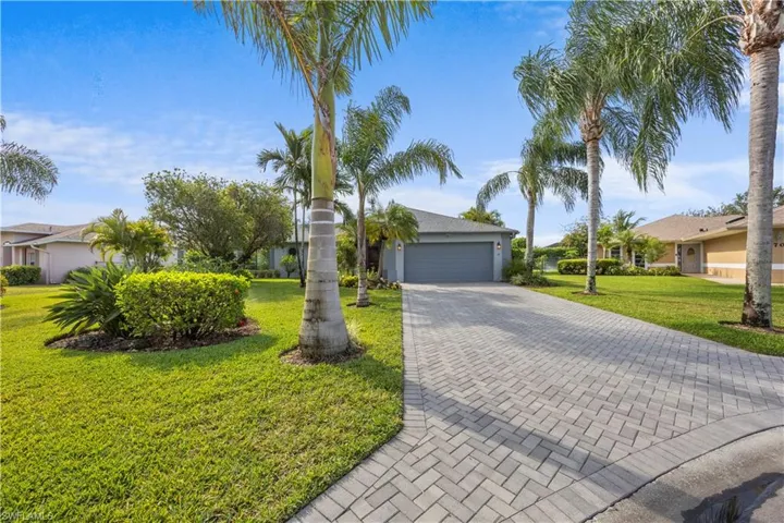 View of front of home with a residential view, a front lawn, decorative driveway, and a garage