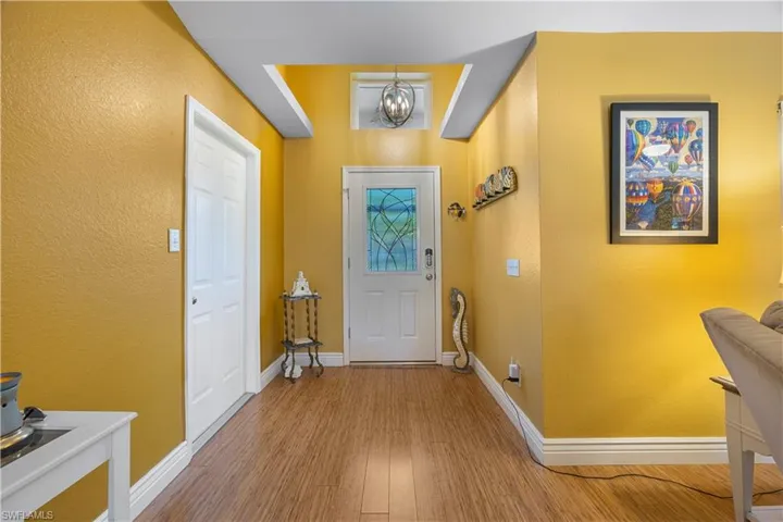 Foyer entrance featuring a chandelier, baseboards, wood finished floors, and a textured wall