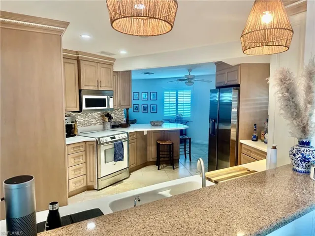 Kitchen with a kitchen bar, a peninsula, stainless steel appliances, decorative backsplash, and recessed lighting