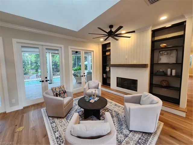 Living area featuring built in features, french doors, light wood-style flooring, ornamental molding, and ceiling fan