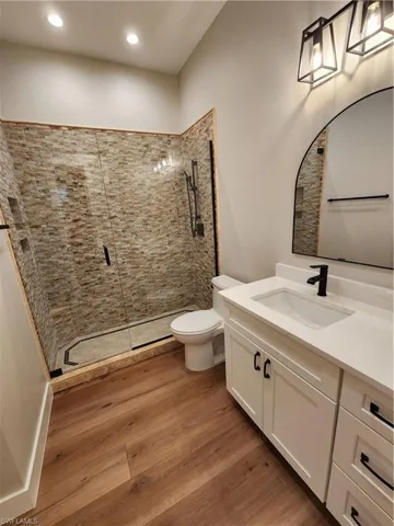 Full bath featuring a shower stall, vanity, and dark wood finished floors