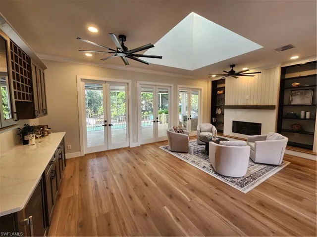 Living room featuring a ceiling fan, light wood-style flooring, a fireplace, recessed lighting, and ornamental molding