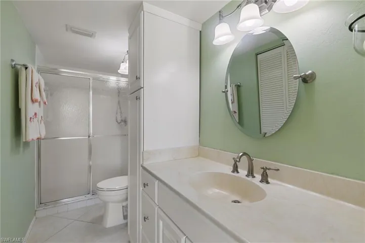 Bathroom with tile patterned flooring, vanity, toilet, and walk in shower