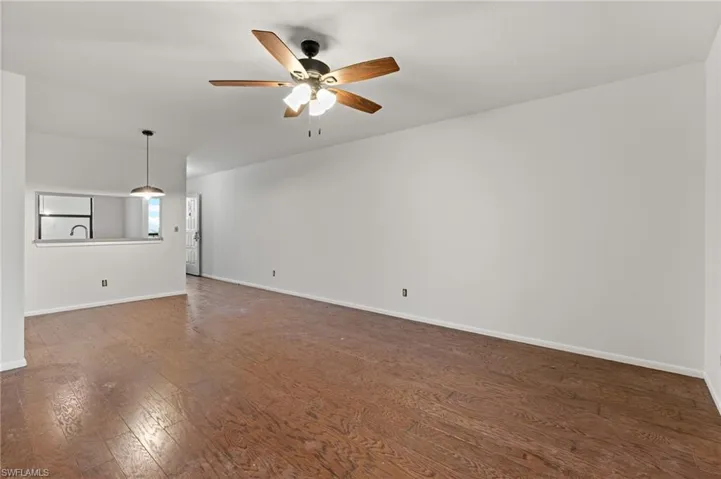 Unfurnished living room with dark wood-style flooring and a ceiling fan