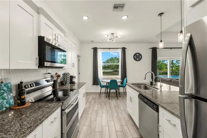 Kitchen featuring a sink, appliances with stainless steel finishes, light wood-style flooring, white cabinets, and decorative backsplash