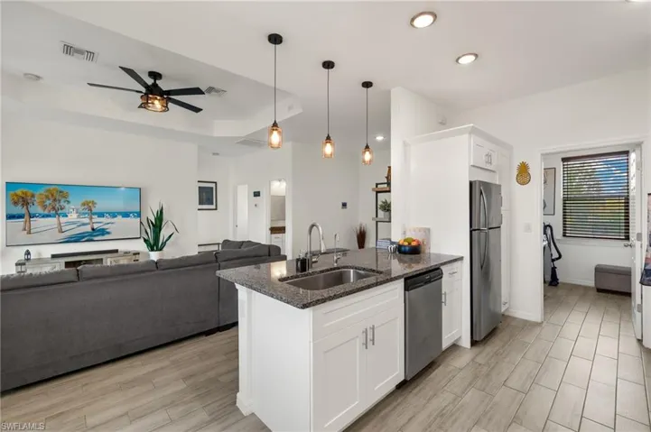 Kitchen with open floor plan, stainless steel appliances, a sink, visible vents, and a ceiling fan