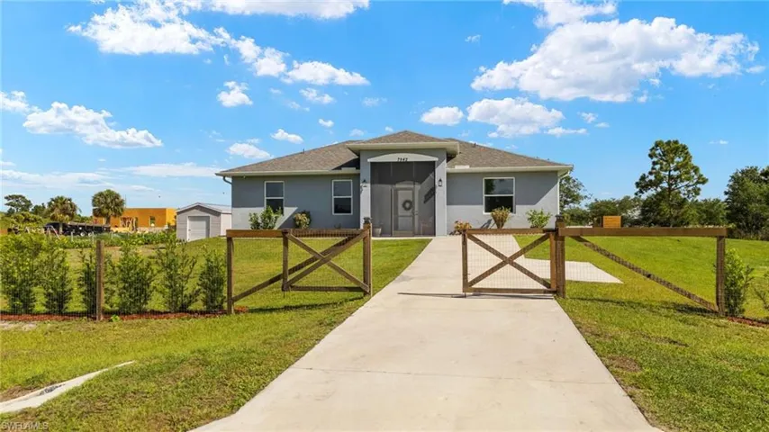 View of front of home featuring a front yard, stucco siding, and a gate