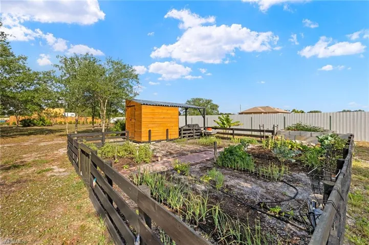 View of yard featuring fence, an outdoor structure, and a vegetable garden