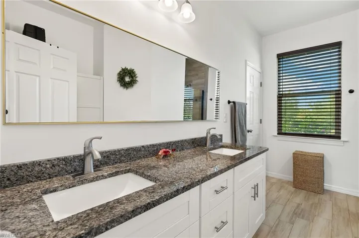 Bathroom with double vanity, wood finished floors, baseboards, and a sink