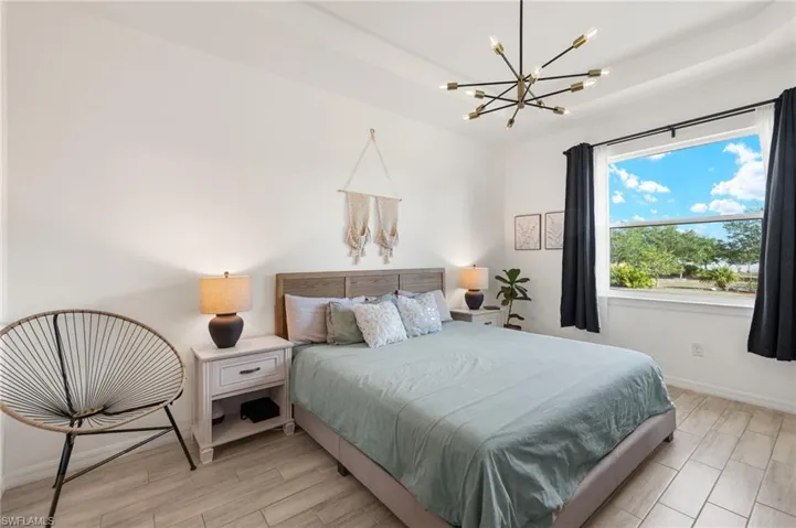 Bedroom with light wood finished floors, baseboards, and a chandelier